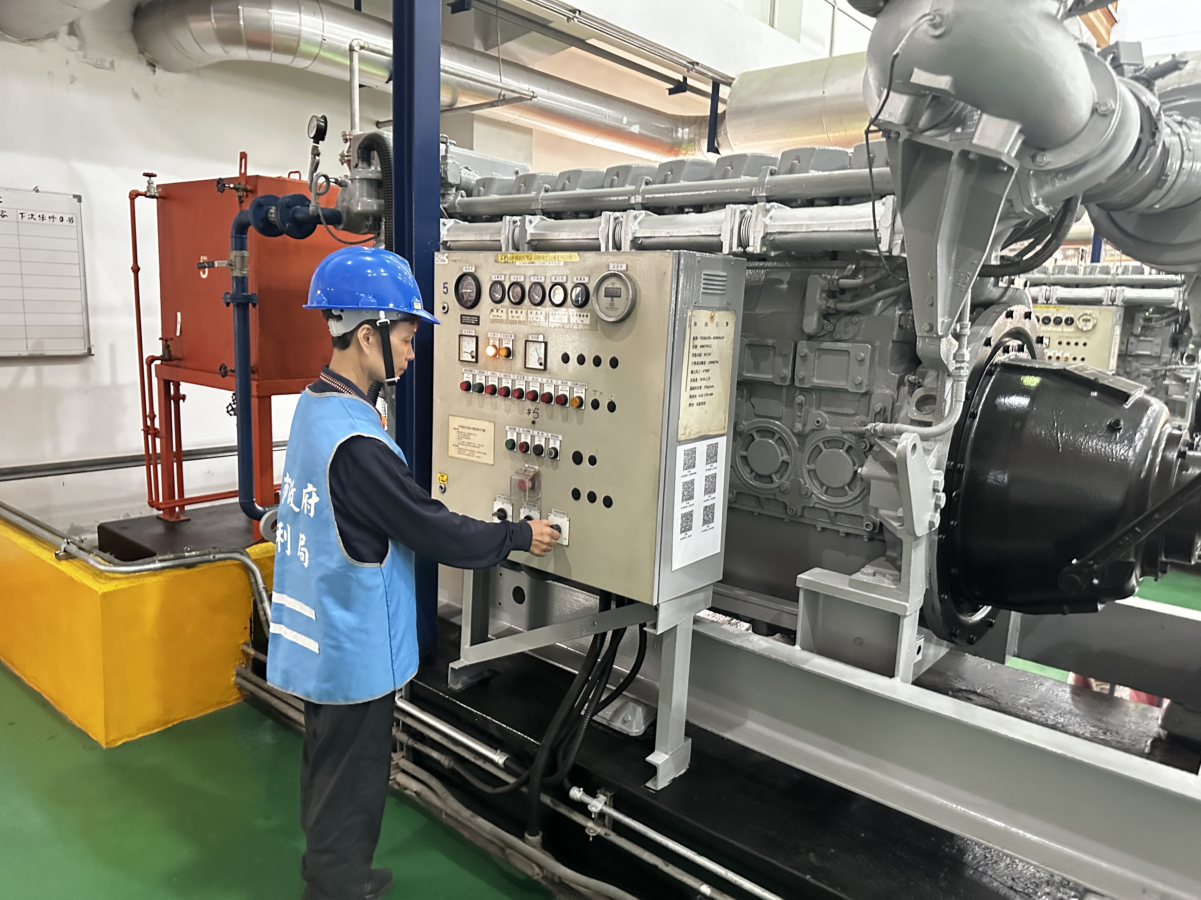抽水站站員操作抽水機的控制盤，以啟動機組